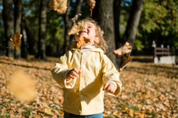 白种人的孩子从秋天的落叶中欣喜图片下载