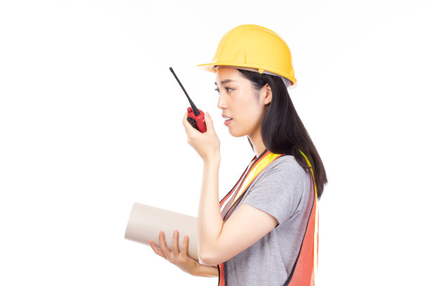 美丽年轻的亚洲建筑女工人黄色头盔和反光背心，使用对讲机与团队工作人员交谈隔离在白色背景。图片下载