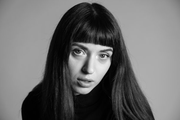 近距离拍摄一个年轻女子的照片，背景是普通的灰色图片下载