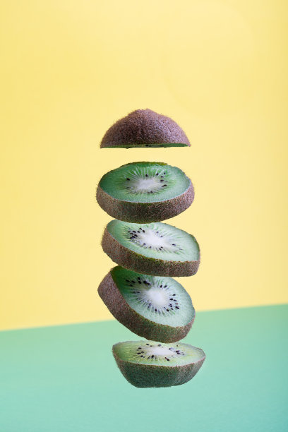 悬浮的猕猴桃切片与明亮的黄色和绿色背景图片下载