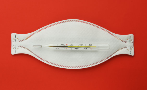 红色背景上带温度计的医用口罩。流感疫情,冠状病毒。温度37.2摄氏度。图片下载