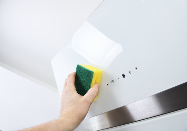 男性的手清洁厨房引擎盖的玻璃表面。清洁和护理白色和玻璃圆顶罩。家管家的概念。图片下载