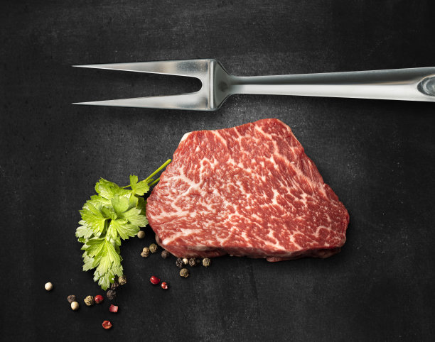 用叉子叉着的神户牛肉片在黑色背景上图片下载