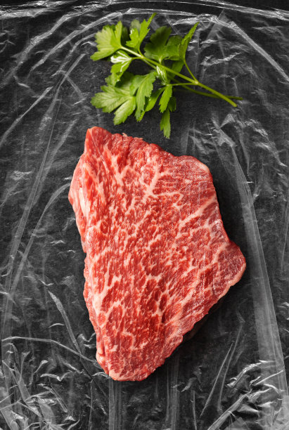 神户牛里脊肉的大理石花纹与欧芹在塑料箔上图片下载