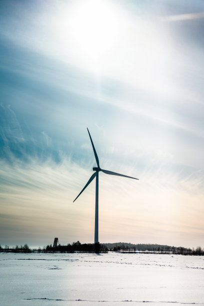 单机的垂直照片停止了风车，没有风。波罗的海冰冻的海岸。大太阳黑子在天空与白蓝色光漫射云。寒冷晴朗的一天，在波罗的海北部。生态能源生产图片下载