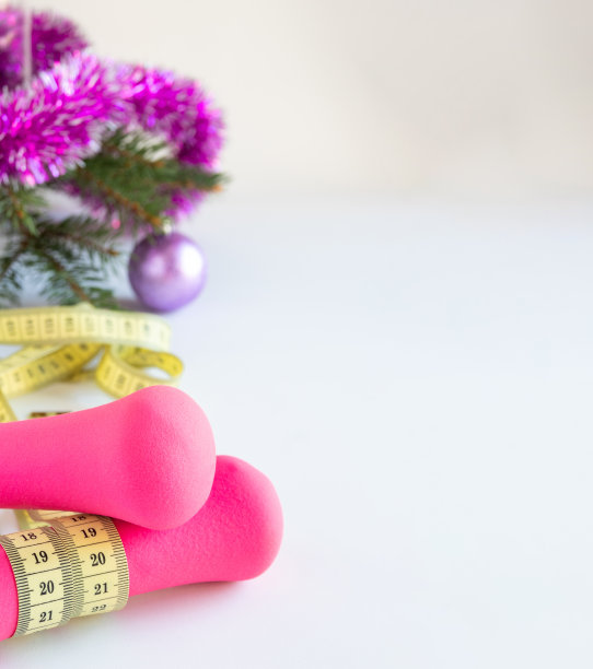 哑铃和一厘米长的丝带白色背景上有圣诞装饰。空间的文本。图片下载