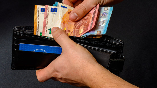 男人的手从钱包里掏钱，黑色的背景和黑色的钱包。图片下载