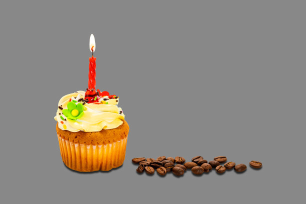 生日蛋糕上点缀着奶油糖霜和彩色彩虹，在灰色的背景上撒上烘培的咖啡豆。图片下载