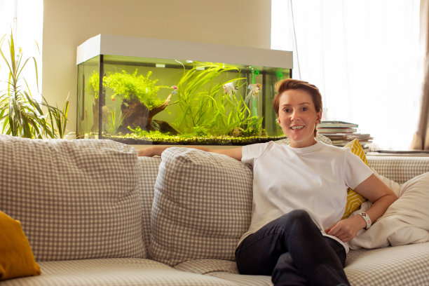 快乐的女人靠在舒适的沙发上靠在鱼缸上休息图片下载