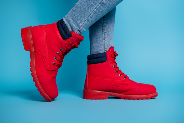 裁剪的资料照片适合女士的腿运动鞋脚尖穿时尚的红色橡胶鞋靴子牛仔牛仔裤孤立的蓝绿色背景图片下载