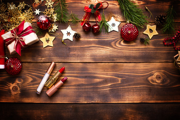 红色唇膏、唇彩和眼睑在木制的圣诞装饰背景上。节日为新年化妆，送礼，购物，女人的欲望。文字空间，平铺图片下载