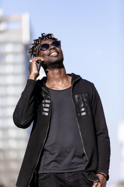 黑色微笑的男人戴着太阳镜在户外使用手机图片下载