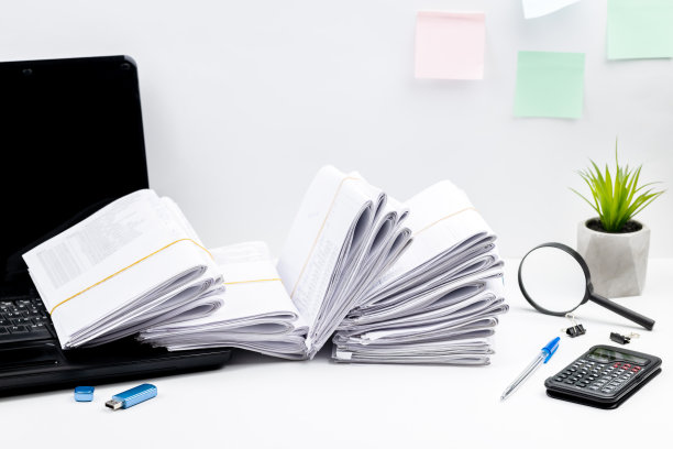 办公室的侧视图，里面有笔记本电脑，办公用品和一大堆文件。影棚拍摄。文书工作超载的概念。税务报告的概念图片下载