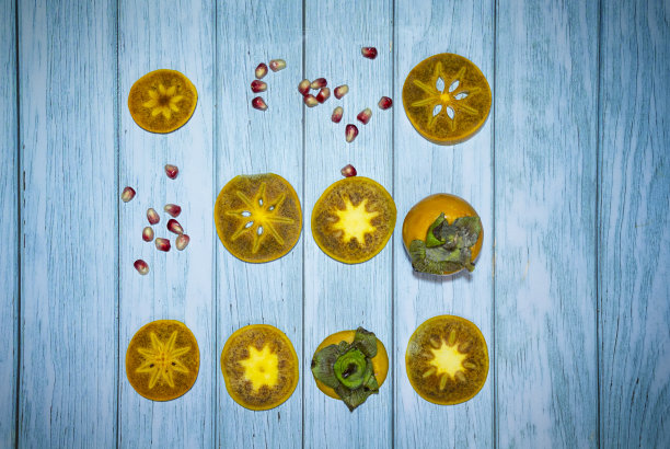 一套黄色的柿子和橘子在绿松石木制的背景，选择性的焦点。图片下载