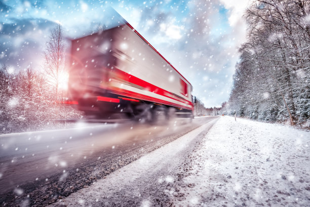 在阳光明媚的冬日早晨，卡车行驶在柏油路上图片下载