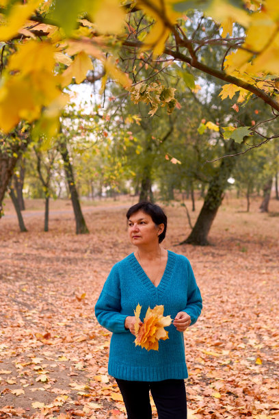 美丽的白种女人在秋天的户外散步。图片下载
