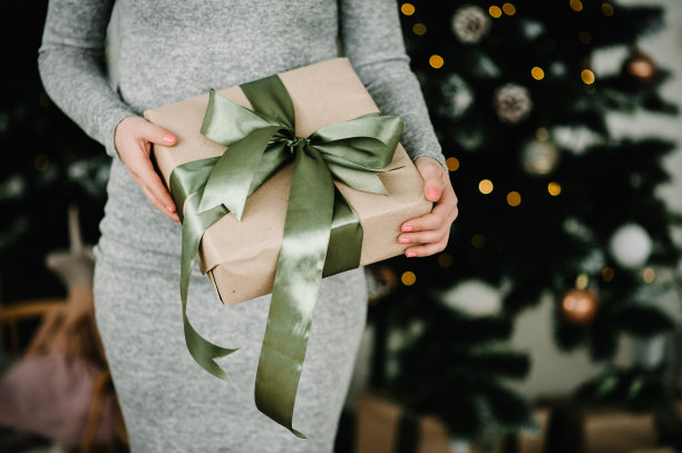 女人手里拿着圣诞礼物或新年装饰的礼品盒。健美的图片。圣诞快乐，节日快乐。关闭了。图片下载