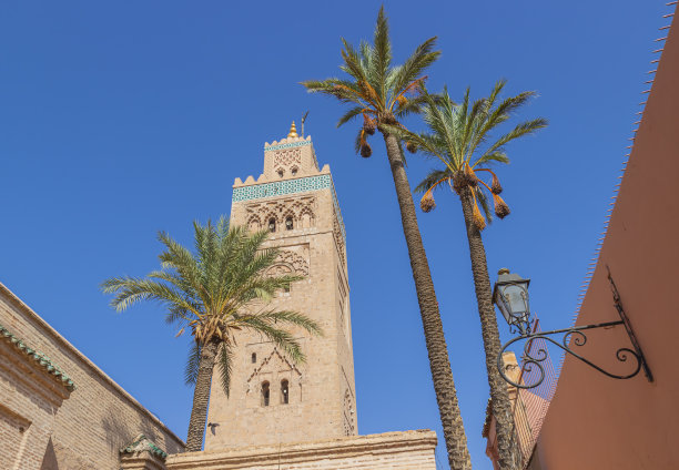 摩洛哥马拉喀什麦地那的库杜比亚清真寺尖塔。在摩洛哥旅行的背景。椰枣树和东方建筑映衬着蓝天。图片下载