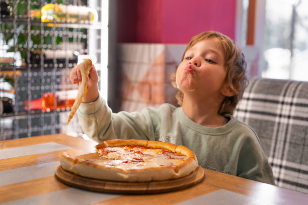 可爱的男孩在快餐店吃披萨。图片下载