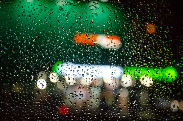 在一幢绿色建筑的背景下，雨点打在玻璃上。图片下载