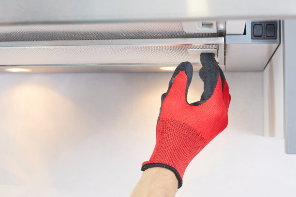 工人在厨房的抽油烟机上安装过滤器。杂工从排气罩上拆卸过滤器。炊具罩修复。图片下载