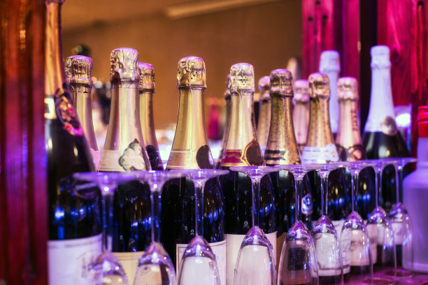 五彩缤纷的香槟酒瓶排成一排，酒杯搭配，派对庆祝概念色彩各异图片下载