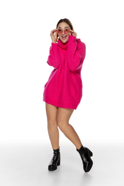 美丽的年轻女子在明亮的粉红色舒适的毛衣，长袖孤立在白色工作室背景图片下载