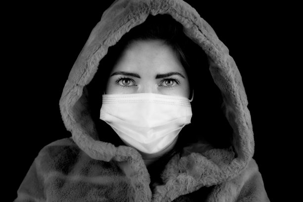 一名美丽的年轻女子身穿冬季夹克，戴着冠状病毒(Covid-19)概念口罩，黑白两色图片下载