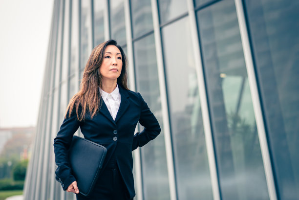 严肃的日本女商人走在摩天大楼旁，金融的女性CEO走在城市里，女性的概念肯定在金融的世界里，成功没有性别歧视图片下载