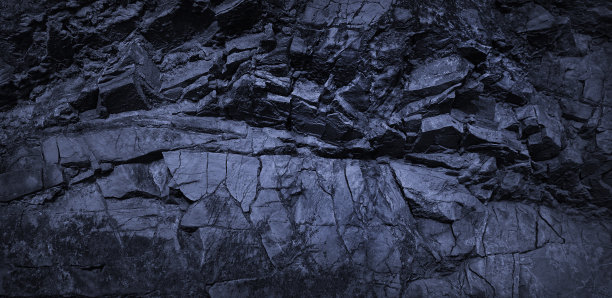 深蓝色的岩石背景。黑白色调的岩石石纹理。崩塌风化的山体表面。特写镜头。图片下载