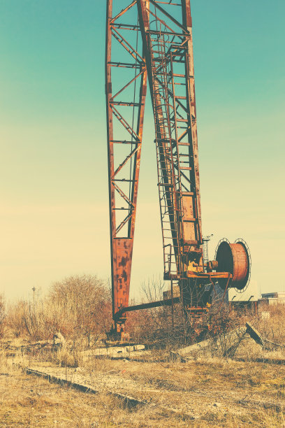 旧的，生锈的门式起重机在铁路上，一个废弃的混凝土工厂。危机、经济崩溃和生产能力的关闭导致了崩溃。全球灾难。一张古老照片的效果。图片下载