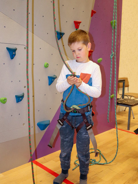 一个小男孩试图把绳子系在攀爬的挽具上图片下载