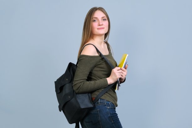 灰色背景上的微笑大学生背包肖像图片下载