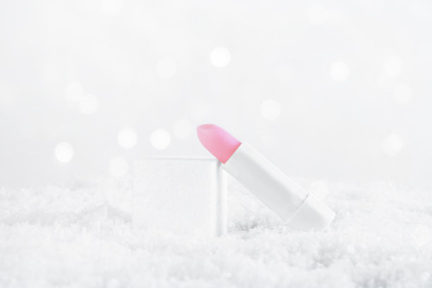 一管白色的粉色唇膏可以保护和滋养嘴唇。冬季化妆品。在雪中模拟容器。给女性的圣诞礼物想法。本空间图片下载