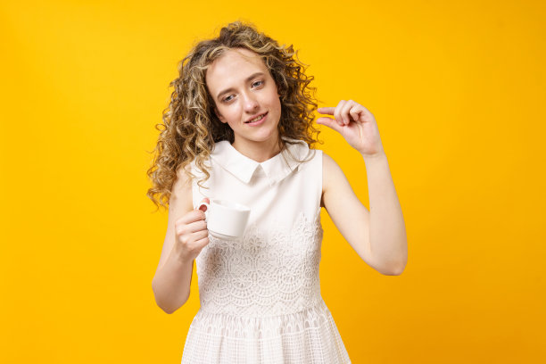 一个年轻女子手里拿着一杯咖啡，她拿出一个小东西，需要多加注意，展示了一个看不见的小东西。图片下载