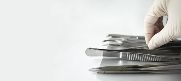 模板水平横幅手术器械在白色背景，文字空间。戴手套的手拿工具。医用夹，手术刀，持针器。图片下载