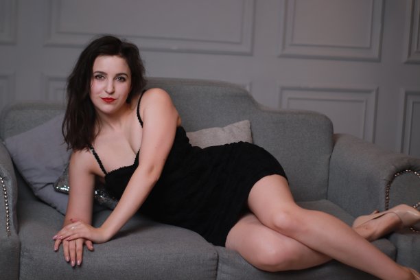 性感迷人的黑发在黑色紧身连衣裙在灰色的沙发在一个装饰大星星的灰色房间。工作室拍摄图片下载