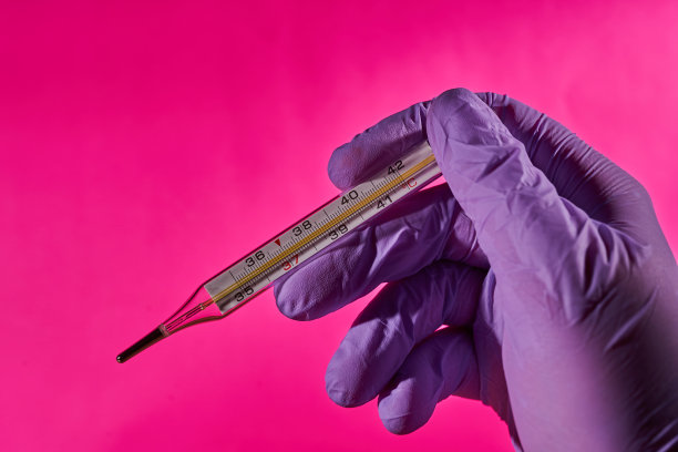 一只戴着医用手套的手拿着温度计来测量体温图片下载