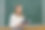 老师拿着书在教室里看着摄像机。数学公式写在黑板上图片下载