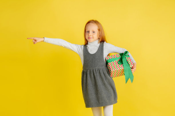 在圣诞节送礼物和收礼物。十几岁的女孩有乐趣孤立在黄色演播室背景图片下载