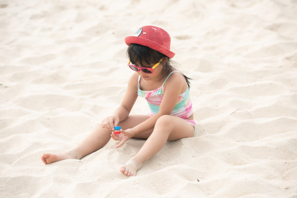 快乐的亚洲儿童女孩在夏天的沙滩上玩白色的沙子图片下载