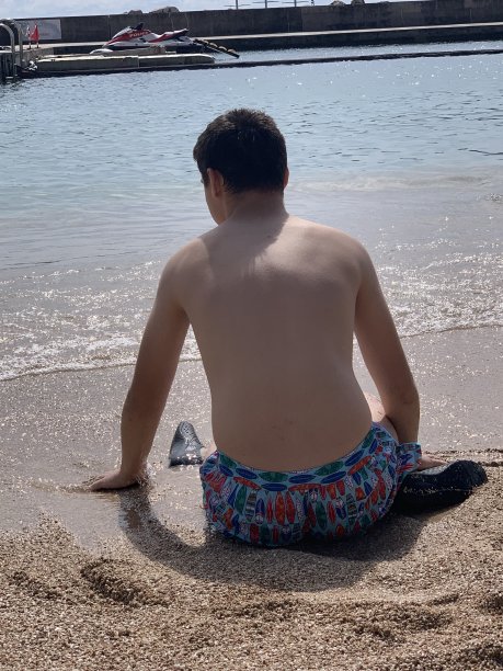 一名患有自闭症的青少年游客坐在摩纳哥蒙特卡洛的Lavrotto海滩上。图片下载