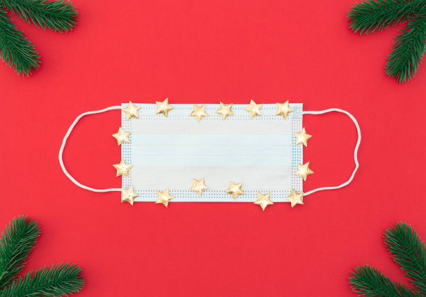 医用防护口罩与金色的星星在红色的背景与杉树枝。2019冠状病毒病全球流行期间的圣诞节。冬天，新年贺卡。平铺风格与复制空间。图片下载