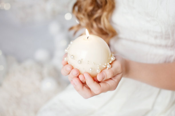 燃烧的蜡烛在一个女孩的手中。圣诞装饰。孩子的手拿着美丽的蜡烛和火。圣诞节的时间。新年和寒假。本空间图片下载