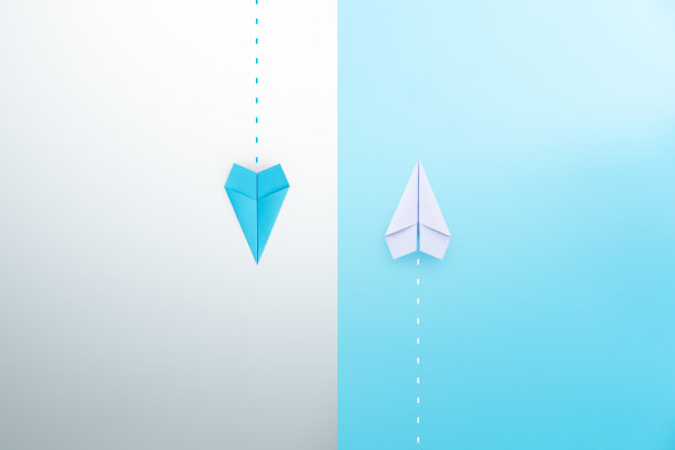 蓝色和白色的纸飞机在不同的方向飞行。不同的意见，不同的观点，概念图片下载
