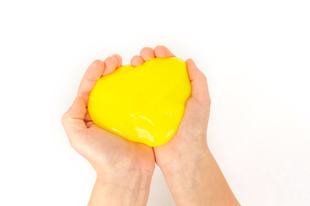 现代玩具叫做黏液。孩子玩透明的黄色黏液。双手拿着一个粘液在白色的背景。有选择性的重点。图片下载