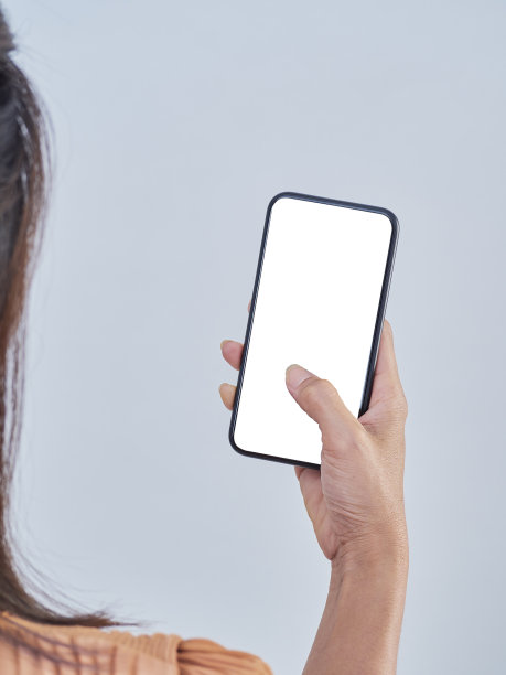 一个女人在灰色背景下拿着智能手机图片下载