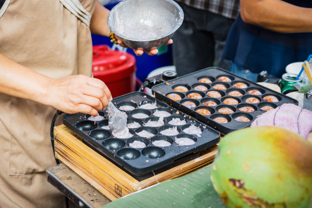 泰国的街头小吃市场，烹制香甜可口的烤椰子米饼。图片下载