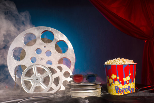 桌子上放着旧电影胶片、爆米花和3d眼镜。专注于眼镜。五彩缤纷的背景。进化电影媒体图片下载