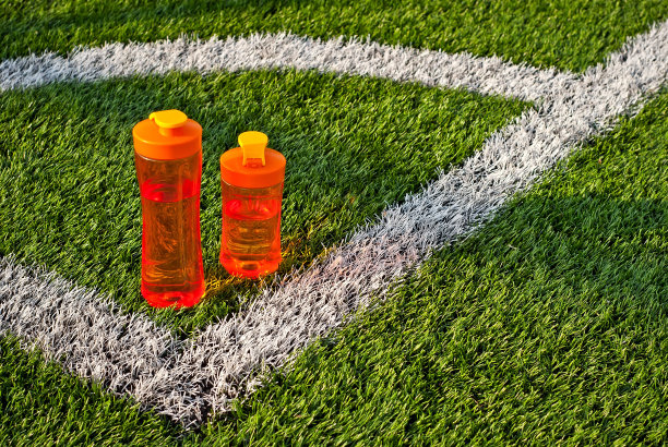 橙色瓶子和水在绿色草地上。健康生活方式的概念。复制空间和地方的文本附近的瓶子。图片下载